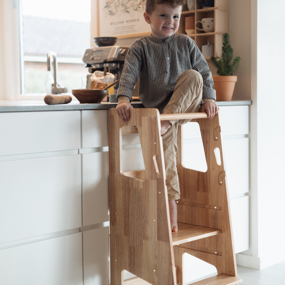 Glad barn i læringstårn i køkkenet