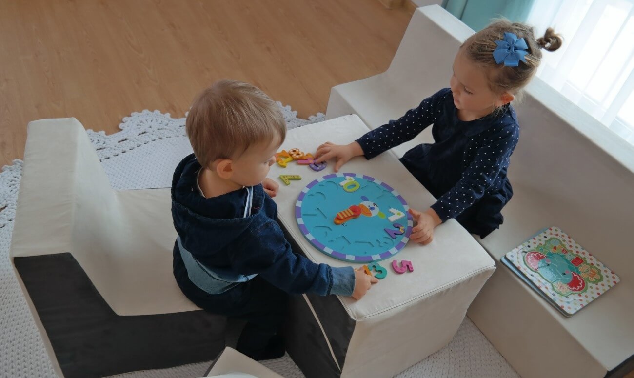 Pige og dreng lærer klokken på legeskumsbordet