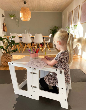 Pige sidder og leger imens hun bruger det foldbare læringstårn som børnebord