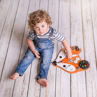 Lille dreng leger med aktivitetstavle, der både kan hænge på væggen eller ligge på gulvet